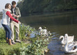 Couple outdoors feeding swans in a lake