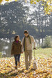 Couple outdoors walking a dog by a lake
