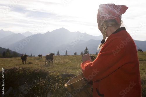 Photo: Woman holding butter tub, cow in background Woman holding butter tub, cow in background