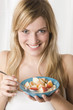 Young woman holding bowl of cereal, smiling, portrait
