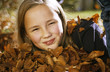 Girl (10-11) with autumn leaves, portrait