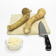 Fresh horseradish with knife and chopping board, close-up