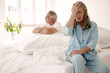 Mature couple sitting on bed (focus on woman in foreground with head in hands)