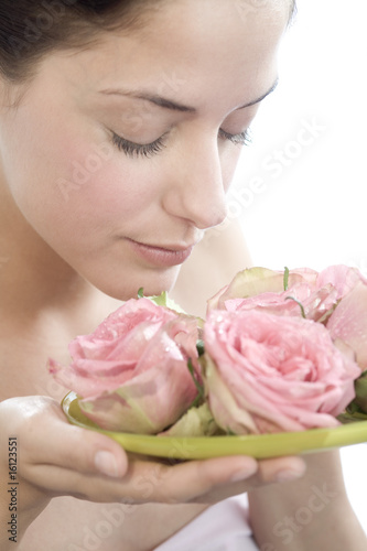 Photo: Young woman smelling rose flowers, eyes closed, close-up Young woman smelling rose flowers, eyes closed, close-up