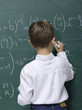 Boy (10-11) writing on blackboard, rear view