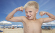 Young boy at the beach flexing biceps