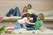 Boy (8-9) and girl (6-7) fighting on carpet, parents in background, portrait