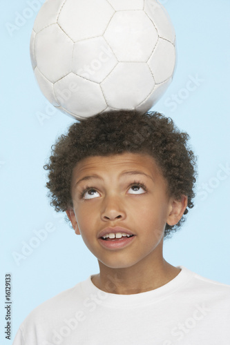 Photo: Young boy indoors balancing soccer ball on his head Young boy indoors balancing soccer ball on his head