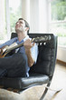 Man sitting in living room playing acoustic guitar