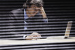Photo: Businessman shot through windowpane with laptop and paperwork looking frustrated Businessman shot through windowpane with laptop and paperwork looking frustrated