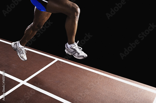 Photo: Runner on race track jumping up in air Runner on race track jumping up in air
