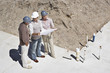 Construction workers viewing blueprints on construction site