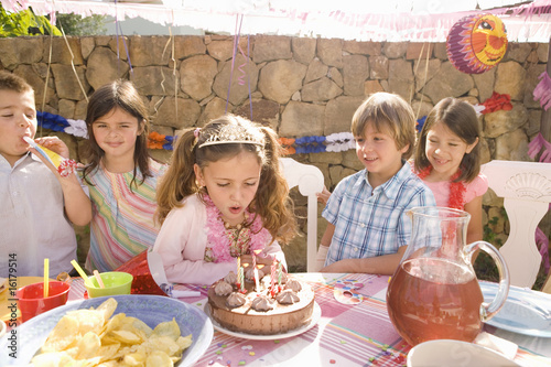Photo: Girl blowing out candles at birthday party Girl blowing out candles at birthday party