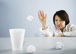 Businesswoman throwing wastepaper into styrofoam cup