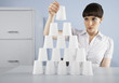 Businesswoman stacking plastic cups into pyramid