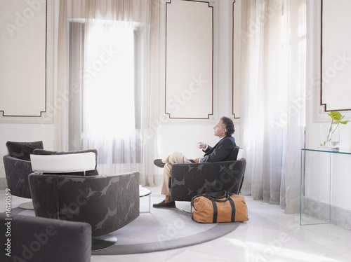 Photo: Man enjoying espresso in modern hotel suite Man enjoying espresso in modern hotel suite