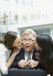 Women kissing surprised businessman