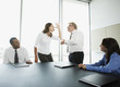 Businesswoman making face at boss in conference room