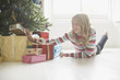 Girl looking at Christmas gifts under tree