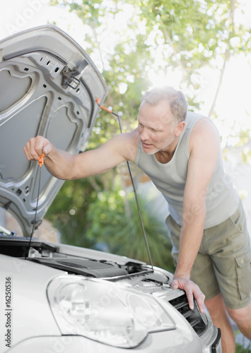 Photo: Man checking oil in car Man checking oil in car