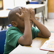 Frustrated boy rubbing eyes in classroom