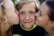Cute blonde boy kissed by two girls