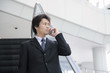 エスカレーターに乗り携帯電話で話をしている男性