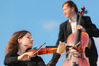 violinist and violoncellist play against sky violinist and violoncellist play against sky