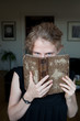 Foto: junge blonde Frau blickt über Buchrand und lächelt junge blonde Frau blickt über Buchrand und lächelt