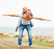 Happy woman being carried on a man's back, hands outstretched