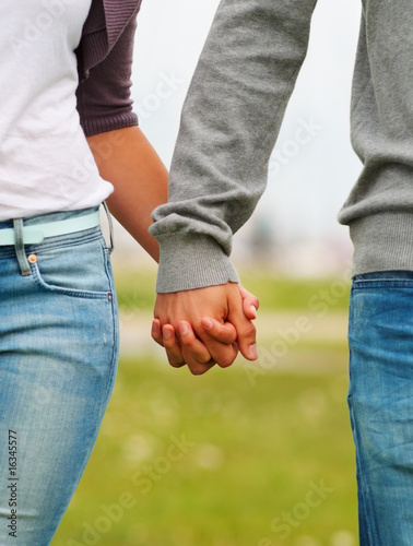 Photo: Mid section image of a couple holding hands, outdoors Mid section image of a couple holding hands, outdoors