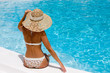 Woman in hat relaxing beside the pool