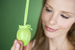 A young blonde woman holding a green Easter egg, close-up