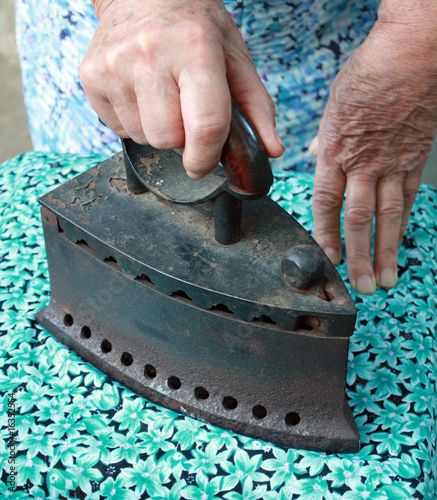 Photo: Old woman irons a cloth Old woman irons a cloth