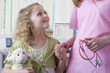 Smiling girl with stuffed animal holding nurseճ hand in examination room