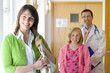 Woman smiling in corridor with doctor and girl in background