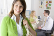 Woman in office smiling with doctor and girl in background