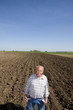 Farmer showing empty pockets in ploughed field