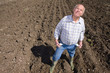 Farmer showing empty pockets and looking up in ploughed field