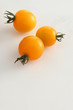 gelbe Kirschtomaten auf weissem Acryl mit Wassertropfen