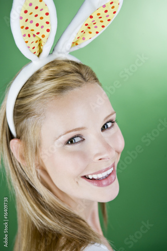 Photo: A young blonde woman wearing rabbit ears, smiling A young blonde woman wearing rabbit ears, smiling