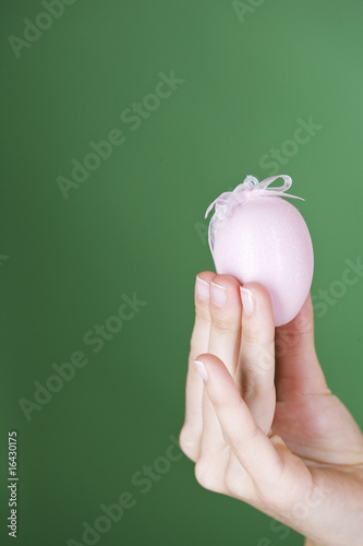 Photo: A woman holding a pink Easter egg, close-up A woman holding a pink Easter egg, close-up