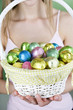 A young woman holding a basket full of Easter eggs