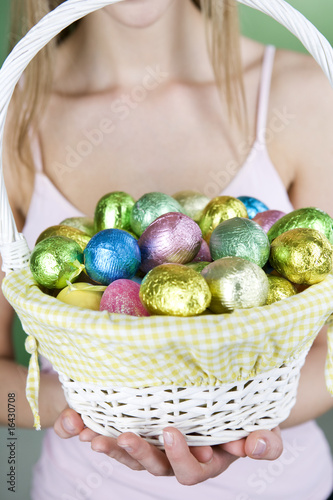 Photo: A young woman holding a basket full of Easter eggs A young woman holding a basket full of Easter eggs