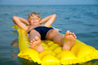 Young boy swimming on mattress in the sea