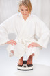 Blond girl in bath robe on scale