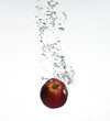 red apple under water with a trail of transparent bubbles.