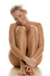 Young naked woman sitting isolated on white background