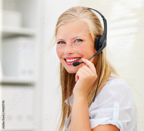 An attractive smiling woman wearing headset in office An attractive smiling woman wearing headset in office