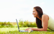 Happy young female using a laptop while relaxing in the garden
